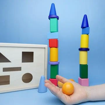 The child built a tower of multi-colored geometric shapes against the background Stock Photos