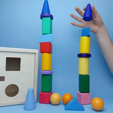 The child built a tower of multi-colored geometric shapes against the background Stock Photos