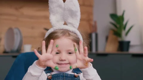 A child with bunny ears is playing with colored eggs in her hands. Easter Stock Footage 236209260