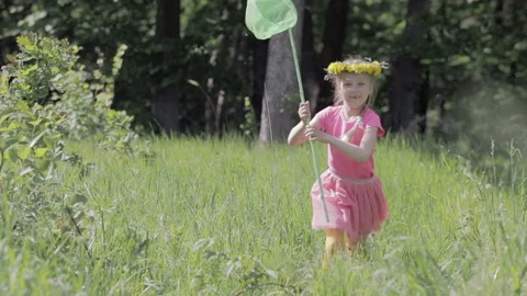 Child with a butterfly net running through a forest glade, on the head of a Stock Footage 89985163
