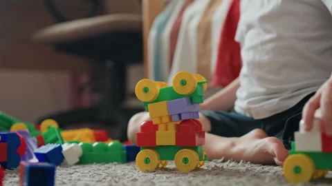 Child carefully stacking bright plastic blocks into train shapes. Young boy Stock Footage 345141282
