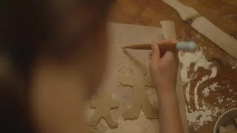 Child carving gingerbread biscuit with head in frame Stock Footage 336374586