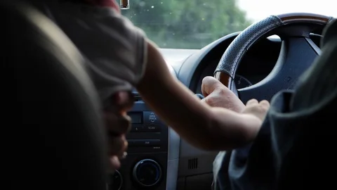 Child chaotic hand playing steering-wheel dangerous with driver driving car Stock Footage 88330894