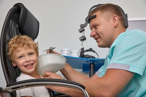 Child cheerfully looks into frame while otolaryngologist washes auricles Stock Photos