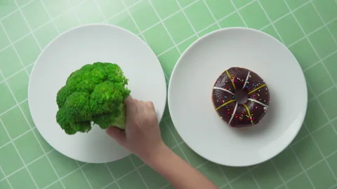 Child is choosing between broccoli and chocolate doughnut Stock Footage 270666551
