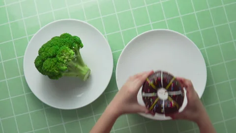 Child is choosing between broccoli and chocolate doughnut Stock Footage 313375748
