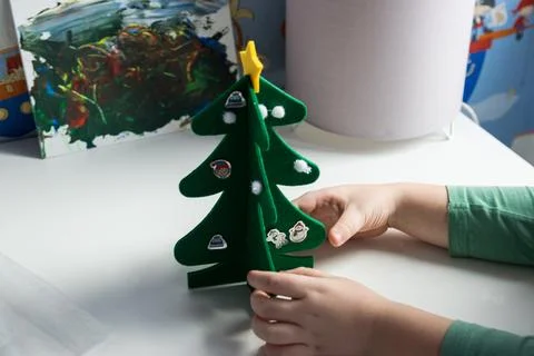 Child with christmas tree sit on the table. Stock Photos