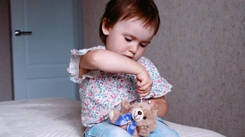 Child cleaning the ears of a toy bear with an ear cleaning stick Stock Footage 258837761