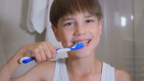 The child cleans his teeth. The boy is brushing his teeth in the bathroom. Stock Footage 77557411