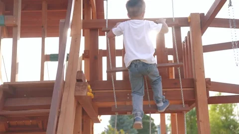 Child is climbing on playground. fun kid park concept. boy climbs onto a wooden Stock Footage 287225504
