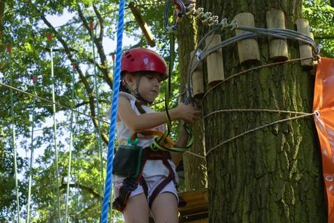Child climbing a tree while using safety gear for an outdoor adventure Foto stock