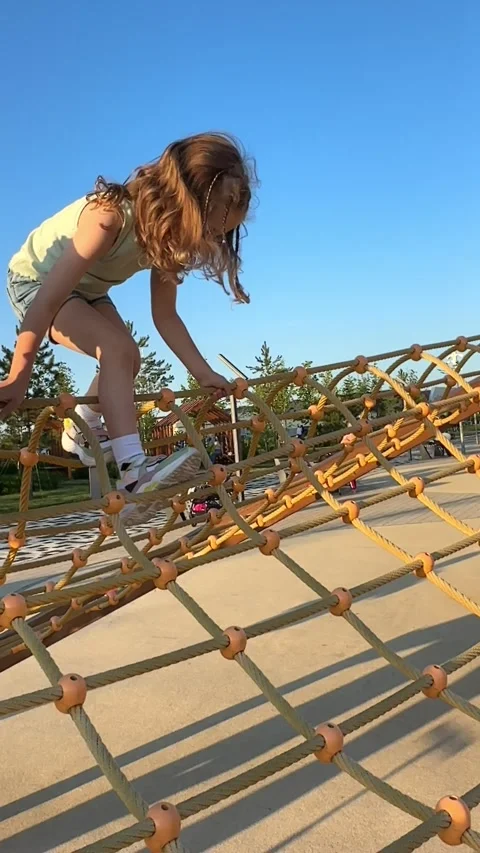 A child climbs up an alpine grid in a park on a playground on a hot summer day.  Stock Footage 244949097
