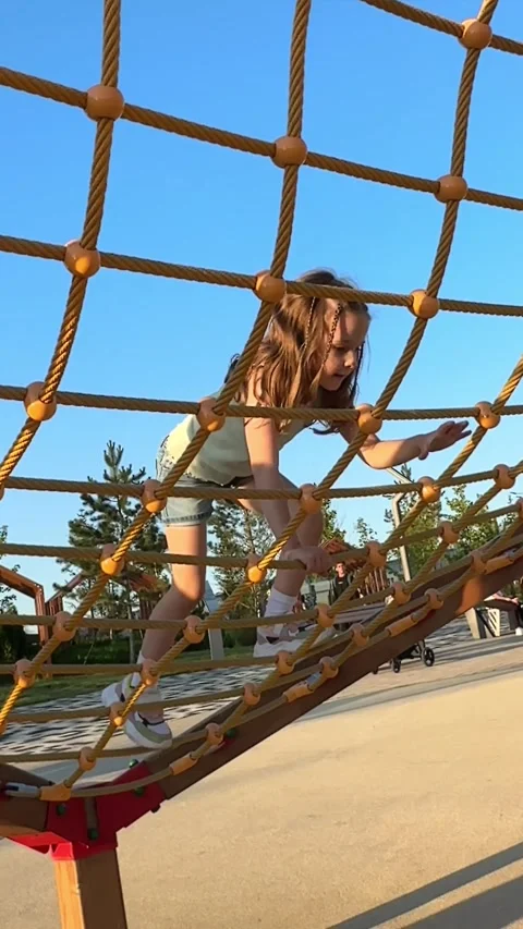A child climbs up an alpine grid in a park on a playground on a hot summer day.  Stock Footage 244949105