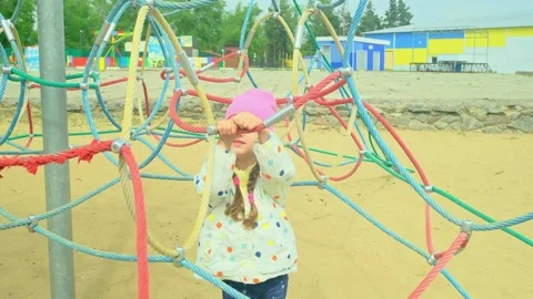 A child climbs up an alpine grid in a park on a playground on summer day. childr Stock Footage 277438997