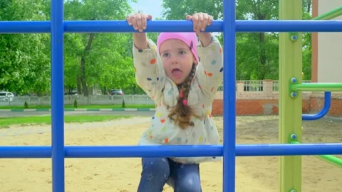 A child climbs up an alpine grid in a park on a playground on summer day. childr Stock Footage 277501568