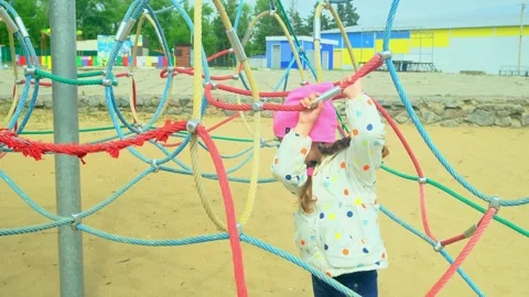 A child climbs up an alpine grid in a park on a playground on summer day. childr Stock Footage 277503512