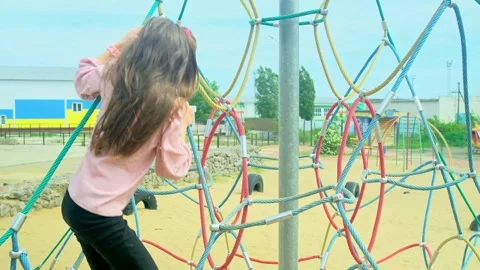 A child climbs up an alpine grid in a park on a playground on summer day. childr Stock Footage 277548985
