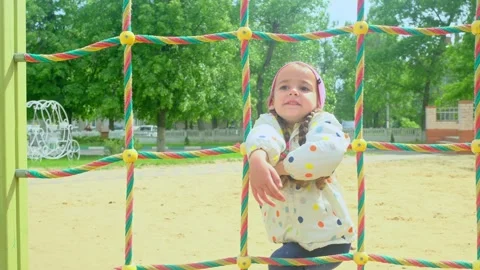 A child climbs up an alpine grid in a park on a playground on summer day. childr Stock Footage 277623663