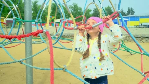 A child climbs up an alpine grid in a park on a playground on summer day. childr Stock Footage 278224714