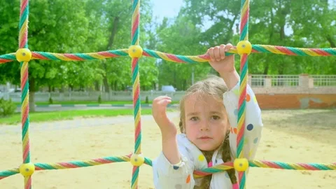 A child climbs up an alpine grid in a park on a playground on summer day. childr Stock Footage 279874105