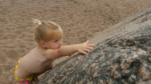 Child climbs on big stone at the beach. Little girl climbing Stock Footage 95335015