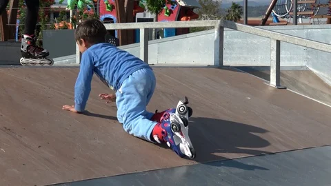 Child climbs up on ramp and stands up on roller blades Stock Footage 106969219