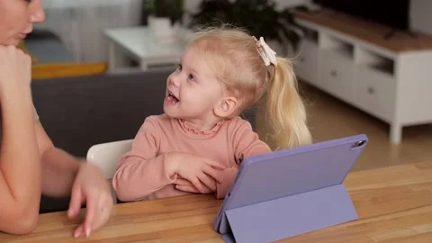 A child with cochlear implants plays with a tablet computer with his mother Stock-Footage 232389965