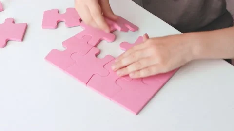 The child collects colored puzzles while sitting at the table. Stock Footage 156869449