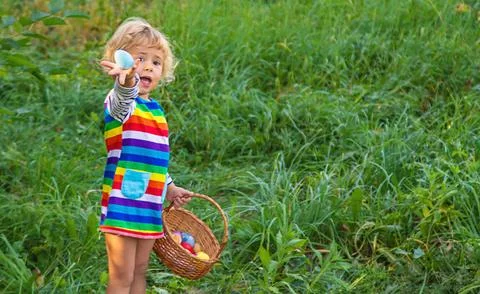 A child collects Easter eggs in the grass. Selective focus. Stock Photos