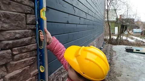 The child in a construction helmet measures the difference between the walls Stock Footage 151679877