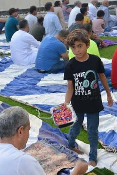 A child contributes sweets during Eid Al Adha religious rituals in the open air Stock Photos