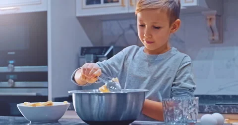 Child cooking at the kitchen. White boy takes a spoon butter and put it to th Stock Footage 150854211