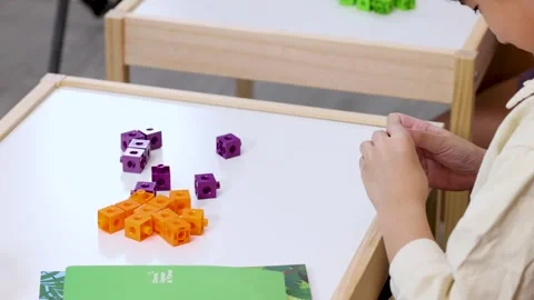 Child Counting Colorful Math Cubes at Classroom Desk Stock Footage 323980439