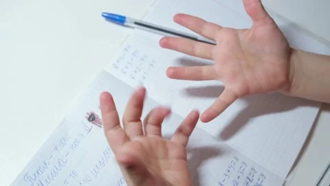 Child counting on fingers while solving basic arithmetic homework 스톡 동영상 332159155