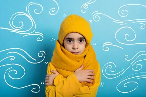 Child covers herself to avoid catching a cold. Cyan background 스톡 사진
