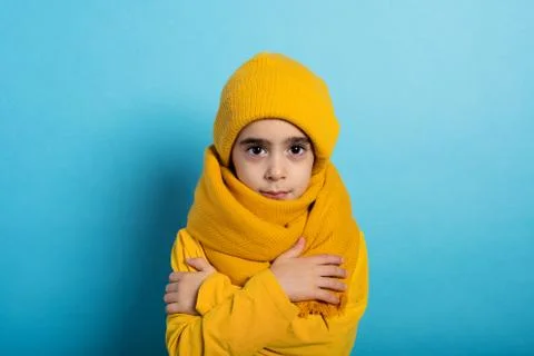 Child covers herself to avoid catching a cold. Cyan background 스톡 사진