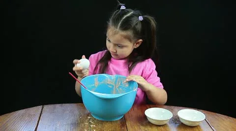 Child cracking an egg into cake batter bowl Stock Footage 11037320