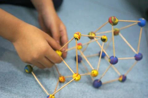 A child creating a geometric structure with craft sticks and colorful model.. Stock Photos
