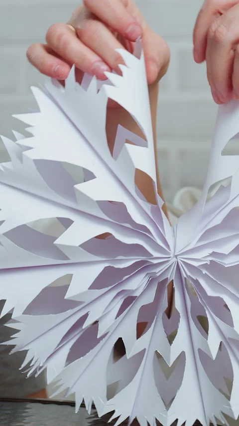 Child creating snowflake, Child carefully crafting paper snowflake on table Stock Footage 329524351