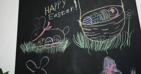 Child creating vibrant Easter chalk art on blackboard Stock Footage 303622345