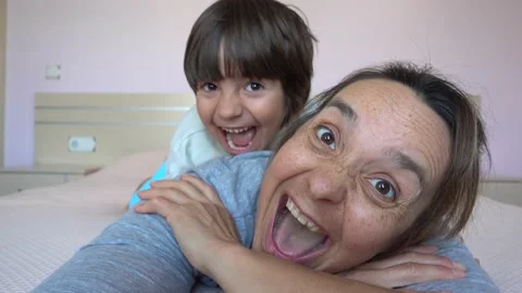 Child creeps over and attacks his resting on bed mother Stock Footage 131357363
