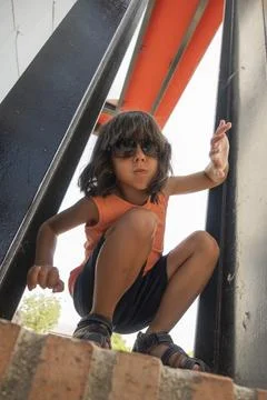 Child crouching and playing inside modern metal structure Fotos Stock