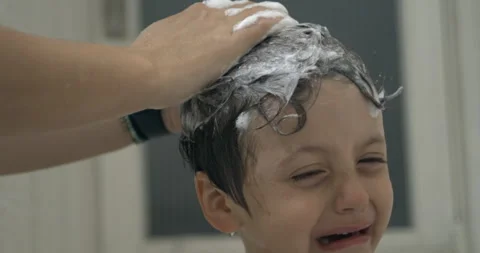 Child crying while mother's hand scrubs his hair with shampoo, displeased e.. Stock Footage 250165769