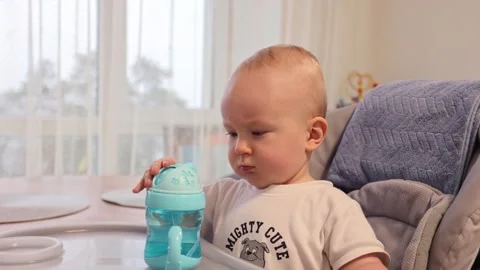 Child curiously looking how to open a baby bottle with water. Stock Footage 281107410