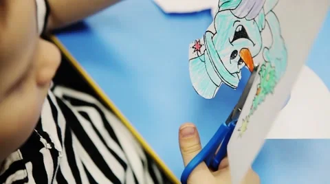 The child is cut with scissors from paper painted snow man. Stock Footage 53747301