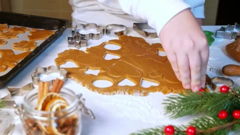 Child cuts heart shaped gingerbread cookie on table, dolly shot Stock Footage 164256151