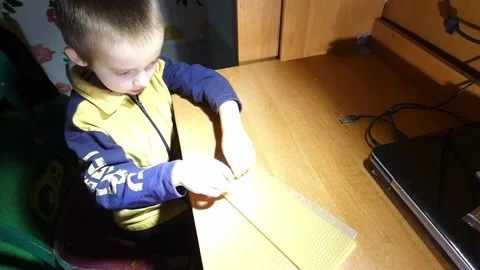 Child cuts paper with scissors in small room during daytime Stock Footage 328416213