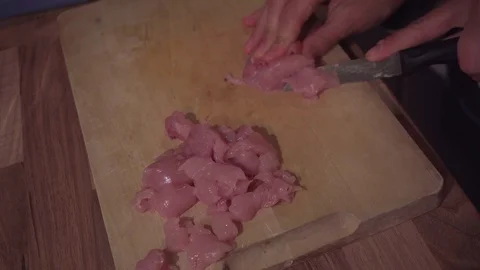 Child cuts raw chicken small for a dish Stock Footage 119332541