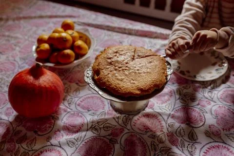 Child cutting homemade cake on patterned tablecloth Stock Photos