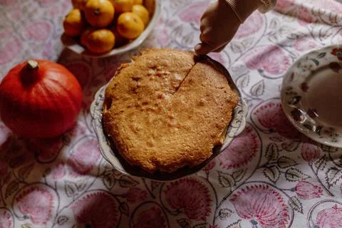 Child cutting homemade cake on patterned tablecloth Stock Photos